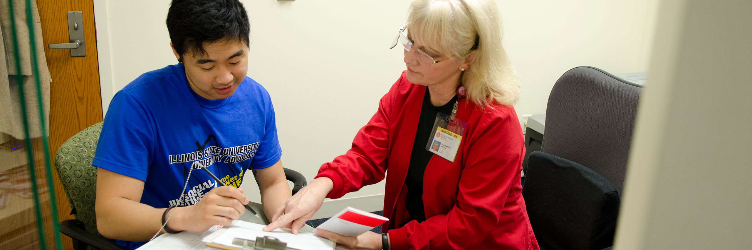 Student signing papers with Health service staff